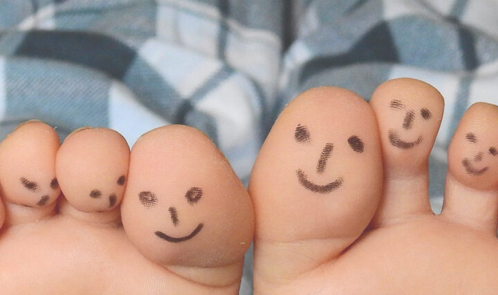 PJ Days - smiley faces drawn on the bottom of toes, legs wearing pjs visible above.