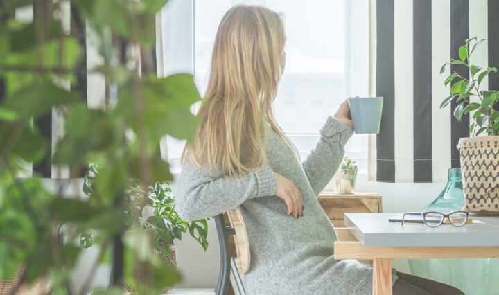 woman looking out of window while drinking coffee in home office... Ways to save money when working from home