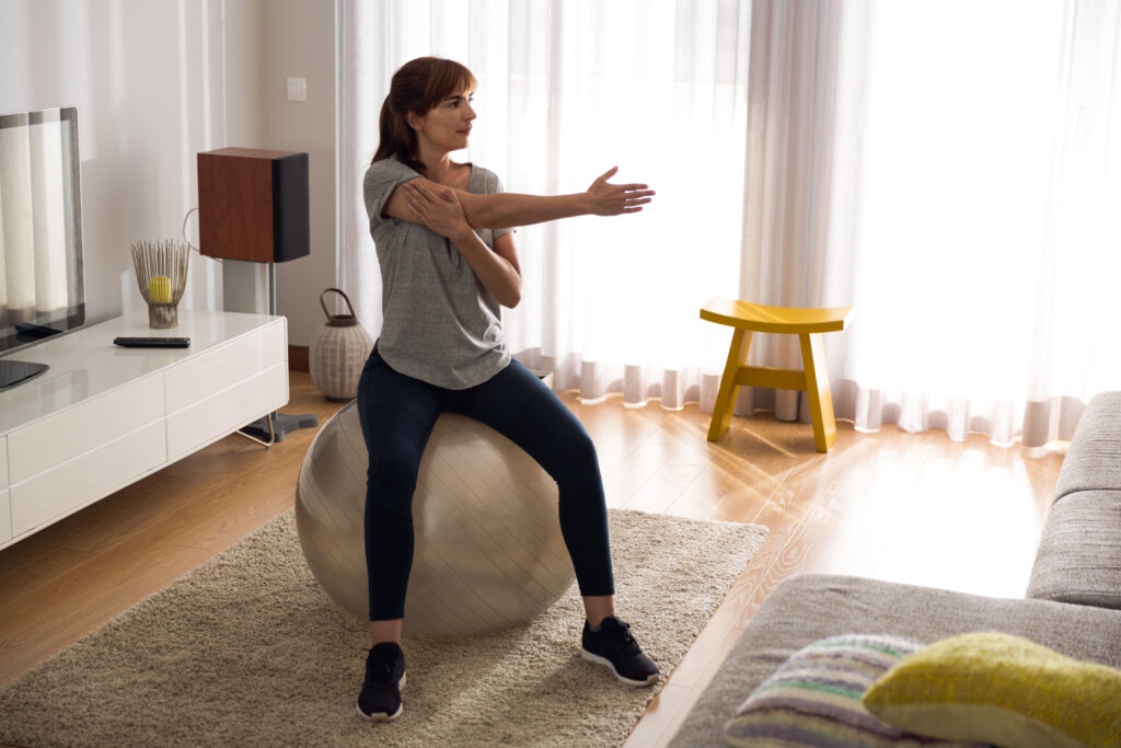 woman at home, exercising on a gym ball after reading tips on stick to your new fitness regime, and exercise while breastfeeding